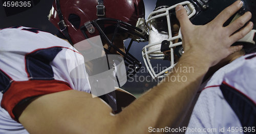 Image of American football players knocking with helmets and having fun