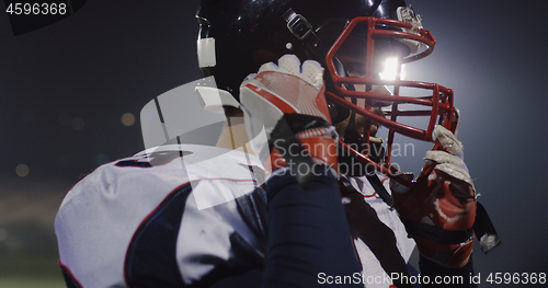 Image of American Football Player Putting On Helmet on large stadium with