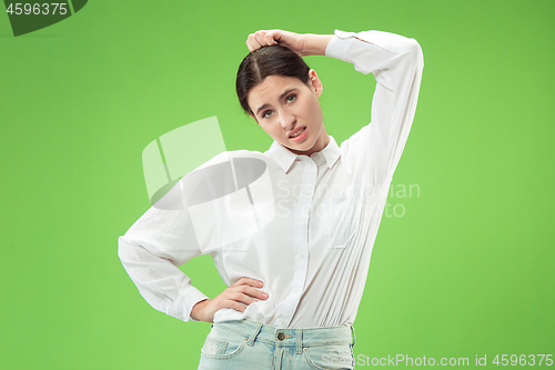 Image of Beautiful woman looking suprised and bewildered isolated on green