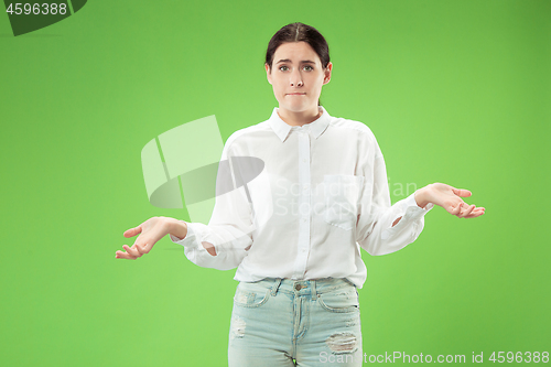 Image of Beautiful woman looking suprised and bewildered isolated on green