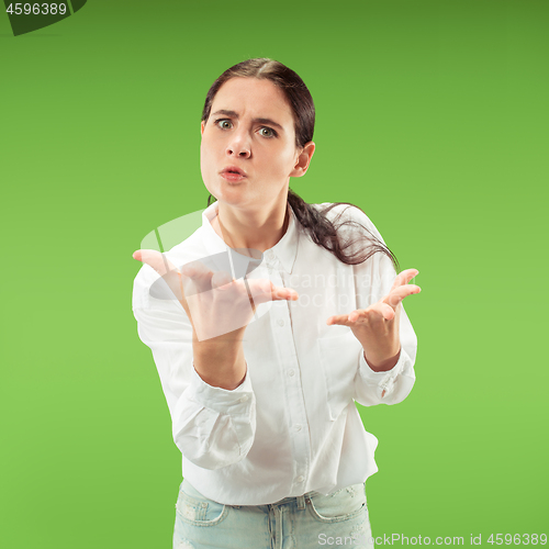 Image of Beautiful female half-length portrait isolated on green studio backgroud. The young emotional surprised woman