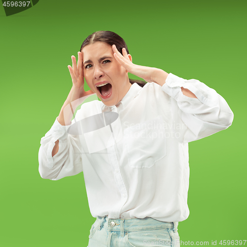 Image of The young emotional angry woman screaming on green studio background