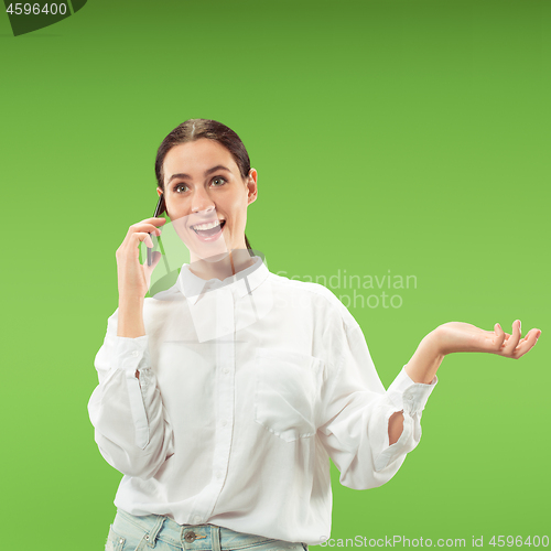 Image of Young beautiful woman using mobile phone studio on green color background