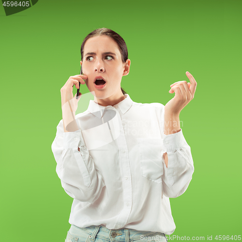 Image of Young beautiful woman using mobile phone studio on green color background