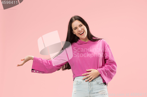 Image of The happy business woman standing and smiling against pink background.
