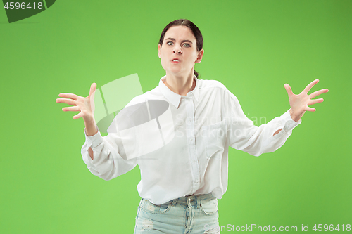 Image of Portrait of an angry woman looking at camera isolated on a green background