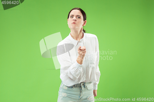 Image of Portrait of an angry woman looking at camera isolated on a green background