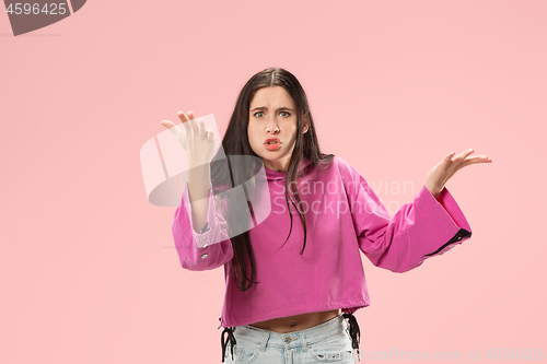 Image of Beautiful female half-length portrait isolated on pink studio backgroud. The young emotional surprised woman