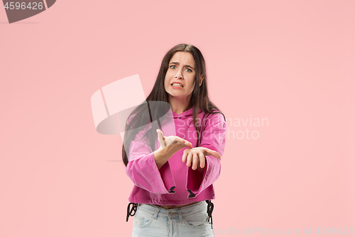 Image of Beautiful female half-length portrait isolated on pink studio backgroud. The young emotional surprised woman