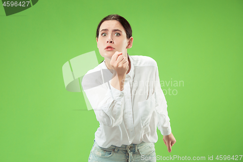 Image of Portrait of an angry woman looking at camera isolated on a green background