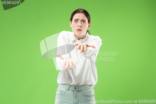 Image of Portrait of an angry woman looking at camera isolated on a green background