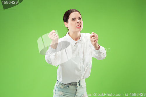 Image of Portrait of an angry woman looking at camera isolated on a green background