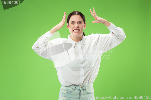 Image of Portrait of an angry woman looking at camera isolated on a green background