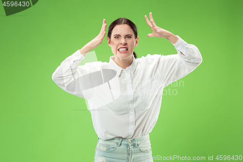 Image of Portrait of an angry woman looking at camera isolated on a green background