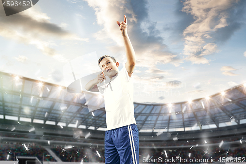 Image of Young boy with soccer ball doing flying kick at stadium