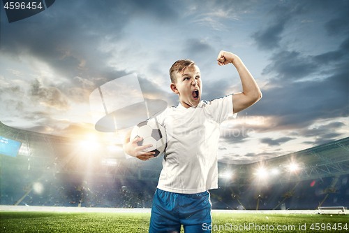 Image of Young boy with soccer ball doing flying kick at stadium