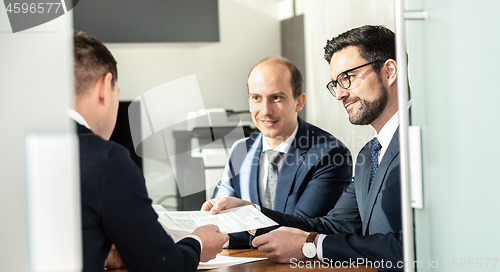 Image of Group of confident successful business people reviewing and signing a contract to seal the deal at business meeting in modern corporate office.