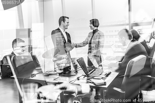 Image of Confident business people shaking hands in moder corporate office.