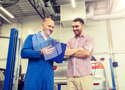 Image of auto mechanic with clipboard and man at car shop