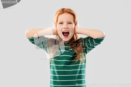 Image of screaming red haired girl closing ears by hands