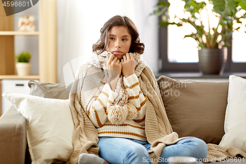 Image of sad sick woman in blanket and scarf at home
