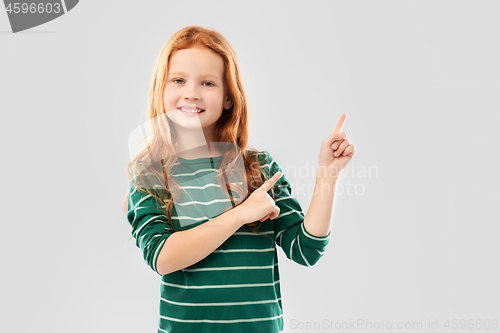 Image of smiling red haired girl pointing fingers upwards