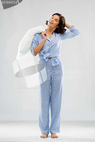 Image of happy sleepy woman in blue pajama holding pillow