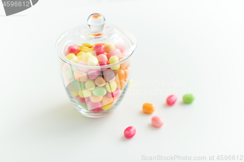 Image of glass jar with candy drops over white background