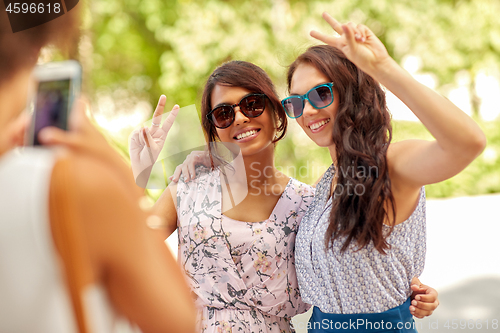 Image of woman photographing her friends in summer park