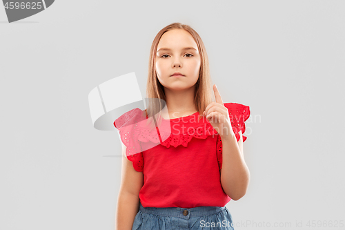 Image of serious girl in red shirt pointing finger up