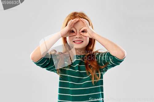 Image of red haired girl looking through finger glasses