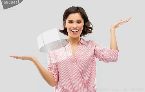 Image of young woman in striped shirt holding something