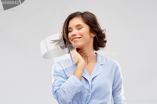 Image of happy young woman in pajama over grey background