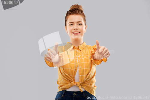 Image of smiling red haired teenage girl showing thumbs up