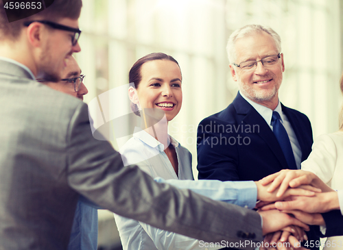 Image of business people putting hands on top in office