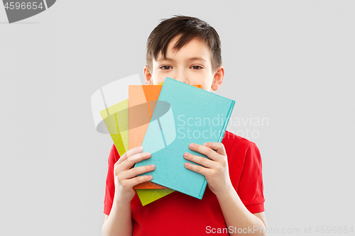 Image of shy schoolboy hiding behind books