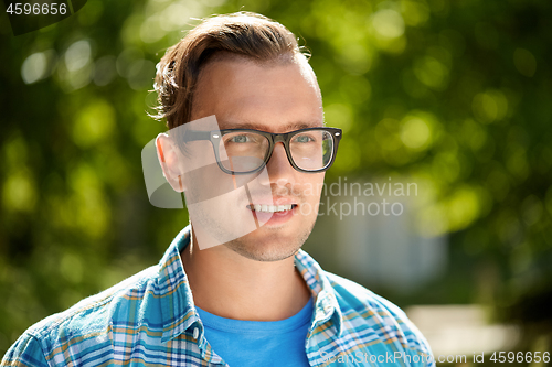 Image of portrait of young man in glasses outdoor in summer