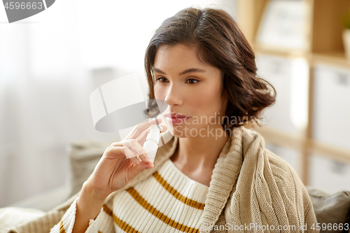 Image of sick woman using nasal spray at home