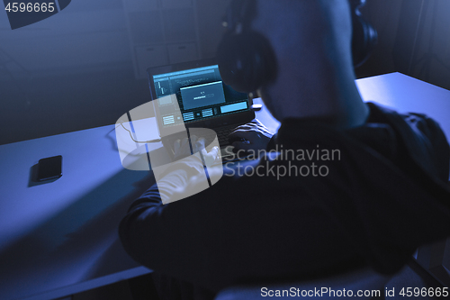 Image of hacker with loading bar on laptop in dark room