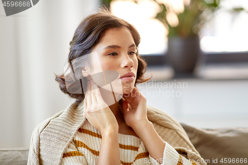 Image of sick woman touching her lymph nodes at home