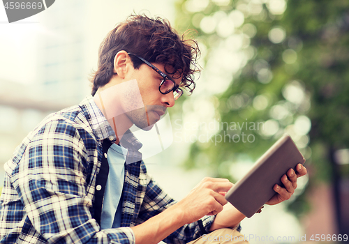 Image of man with tablet pc sitting on city street bench