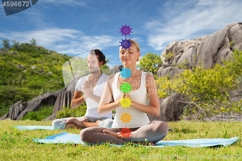 Image of couple doing yoga in lotus pose with seven chakras