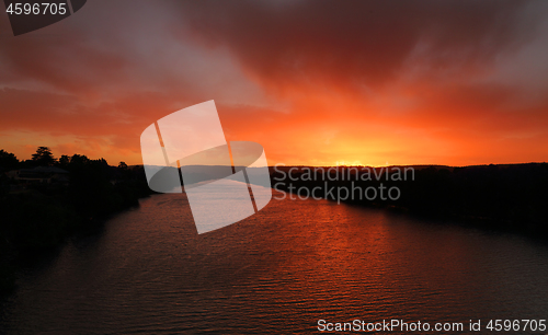 Image of Red sky sunset over river with distant mountains 