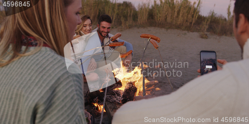 Image of Group Of Young Friends Sitting By The Fire at beach