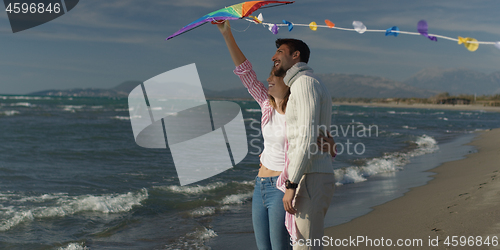 Image of Happy couple having fun with kite on beach