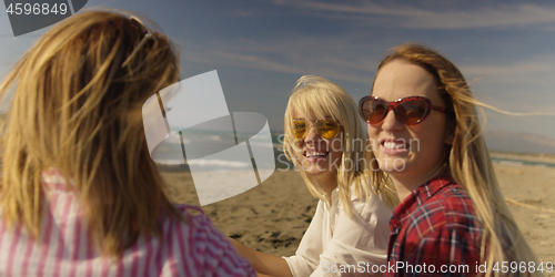 Image of Group of girlfriends having fun on beach during autumn day