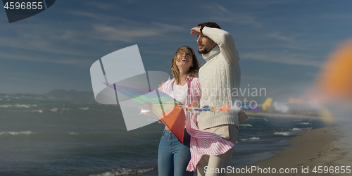 Image of Happy couple having fun with kite on beach