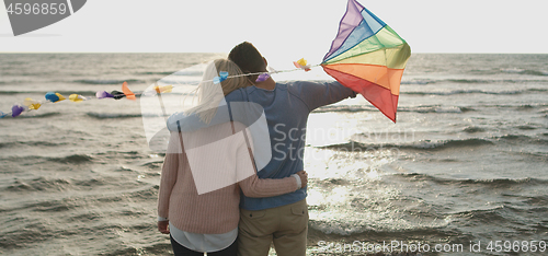 Image of Happy couple having fun with kite on beach