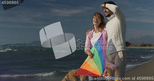 Image of Happy couple having fun with kite on beach