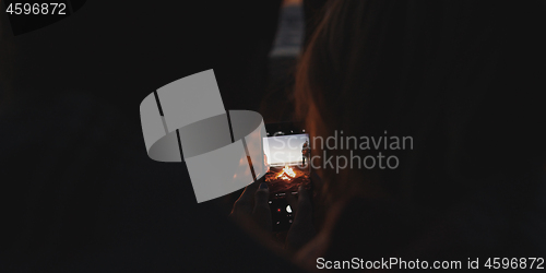 Image of Couple taking photos beside campfire on beach